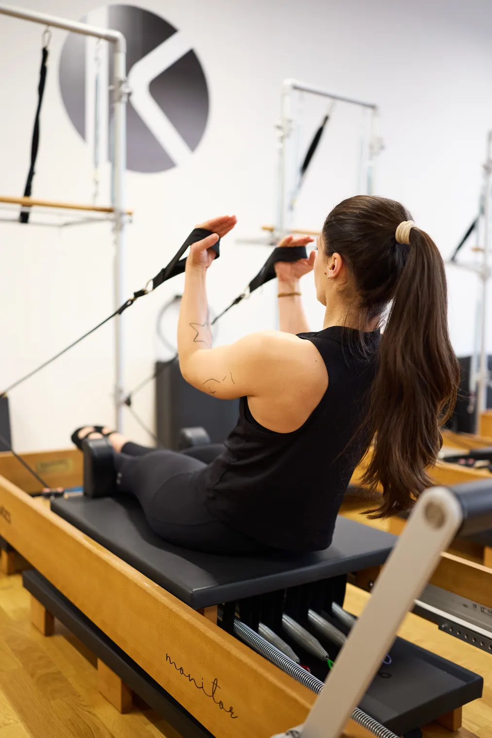 Instructrice de Pilates accompagnant une élève sur le Reformer