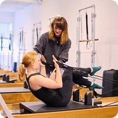 Coach Kysko accompagnant une cliente sur un Reformer