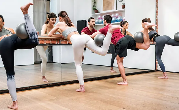 Cours de barre fitness en groupe devant les miroirs